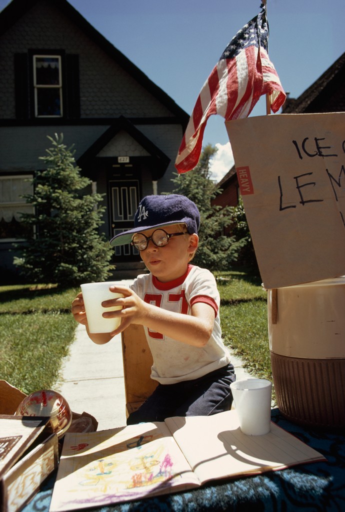 A boy sells lemonade from his front yard stand on Main Street in Aspen, Colorado, 1973