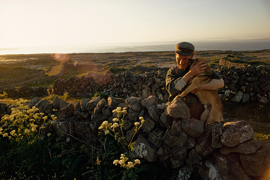 A farmer embraces his dog in his stonewalled field on Inishmore Island in Ireland, March 1971