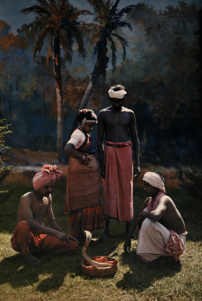 A group of people gather round and watch a snake charmer at work in India, 1923