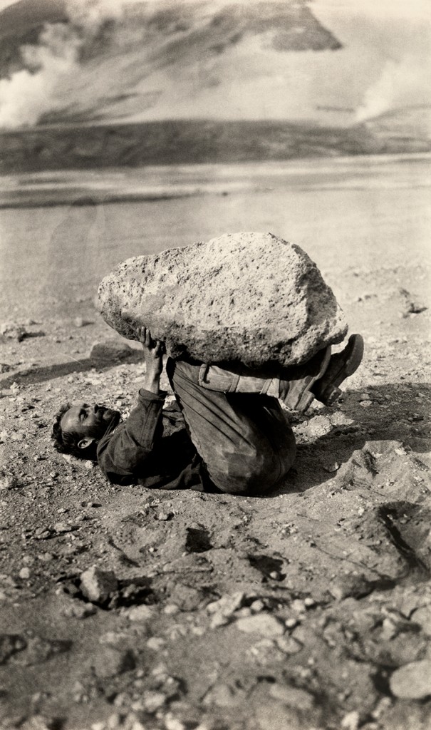 A man balances a piece of pumice rock on his legs in Katmai National Park and Preserve, Alaska, September 1921